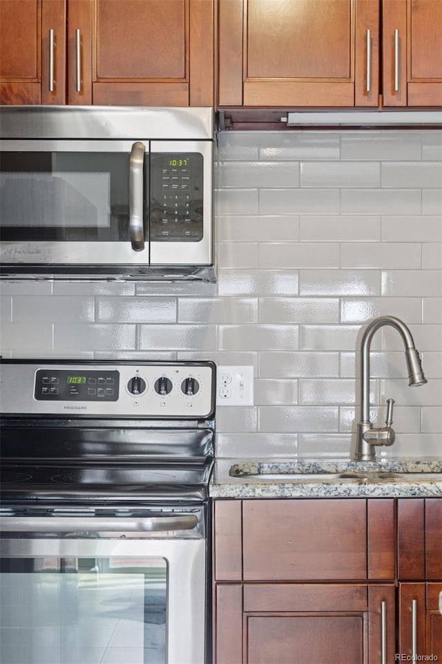2854 N Lowell Blvd, Denver, CO 80211 - kitchen with appliances with stainless steel finishes, backsplash, and light stone countertops