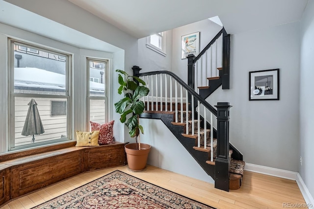 foyer entrance with stairway, wood finished floors, and baseboards