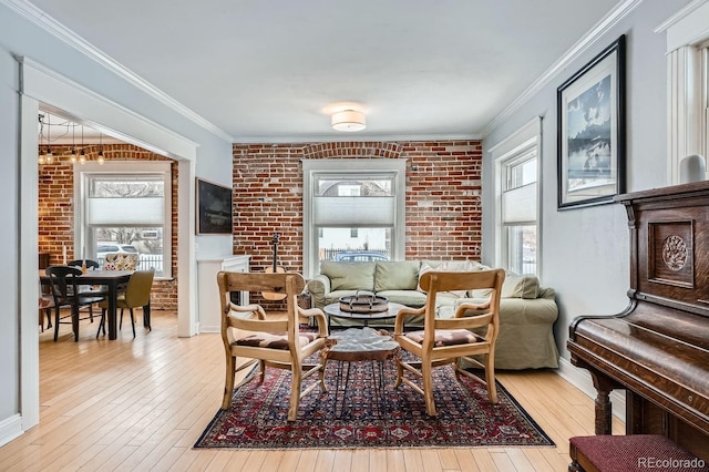 living area featuring brick wall, ornamental molding, light wood-type flooring, and baseboards