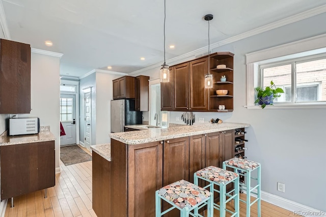 kitchen with decorative light fixtures, open shelves, light wood-style flooring, freestanding refrigerator, and a peninsula