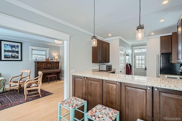 kitchen featuring ornamental molding, light wood-type flooring, hanging light fixtures, and recessed lighting