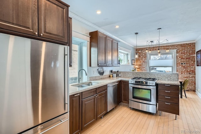 kitchen with appliances with stainless steel finishes, a peninsula, crown molding, pendant lighting, and a sink