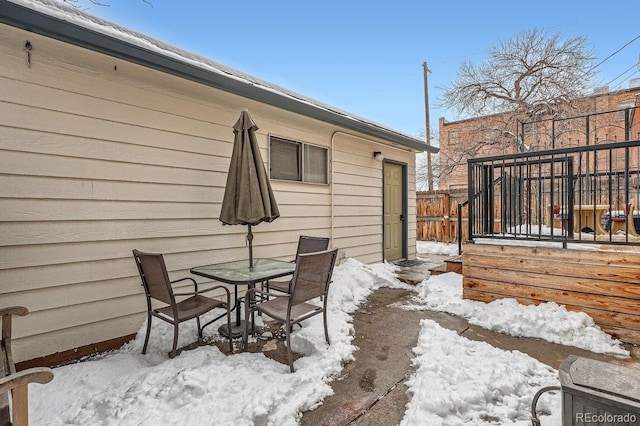 snow covered patio featuring fence