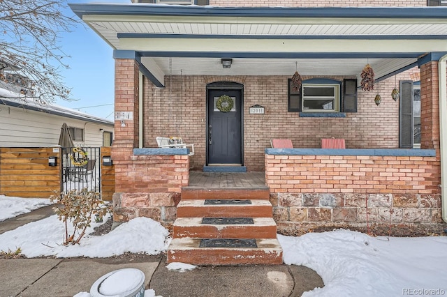 snow covered property entrance featuring brick siding