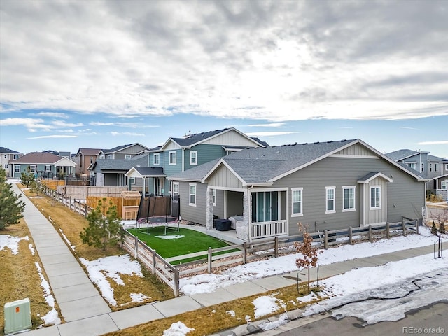 view of front of house with a trampoline, a residential view, and a fenced backyard