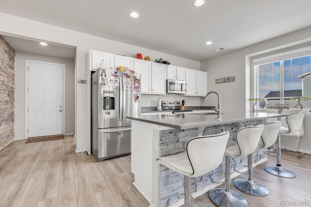 kitchen featuring a kitchen breakfast bar, appliances with stainless steel finishes, a sink, and white cabinets