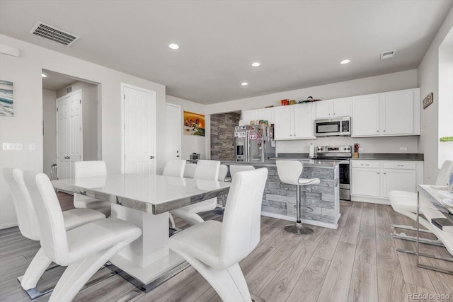 dining area featuring light wood finished floors, visible vents, and recessed lighting