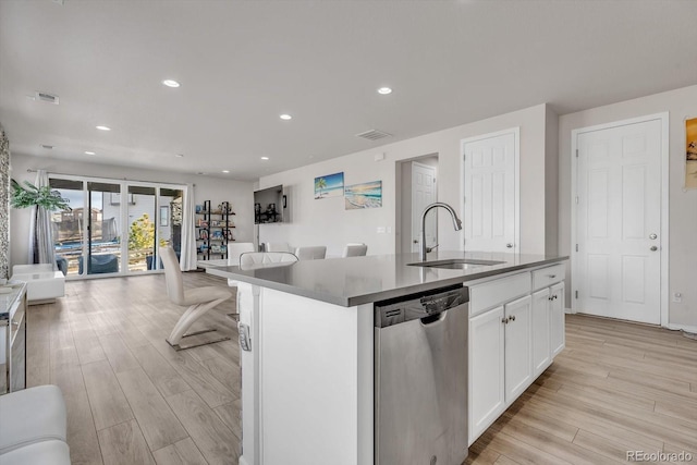 kitchen with open floor plan, dishwasher, light wood-style floors, and a sink