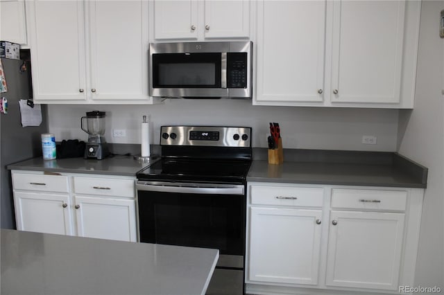 kitchen with dark countertops, appliances with stainless steel finishes, and white cabinets