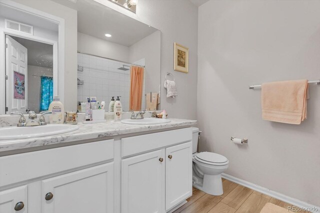 full bathroom featuring visible vents, toilet, wood finished floors, and a sink