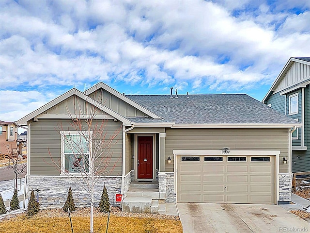 view of front of home with an attached garage, a shingled roof, concrete driveway, stone siding, and board and batten siding