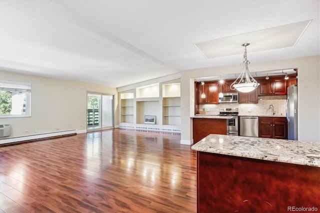 kitchen with a wealth of natural light, dark hardwood / wood-style flooring, stainless steel appliances, and decorative light fixtures