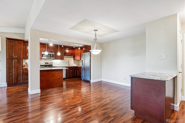 kitchen with light stone counters, dark wood-type flooring, decorative backsplash, appliances with stainless steel finishes, and decorative light fixtures