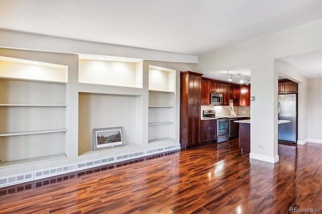 unfurnished living room featuring built in shelves, sink, and dark wood-type flooring