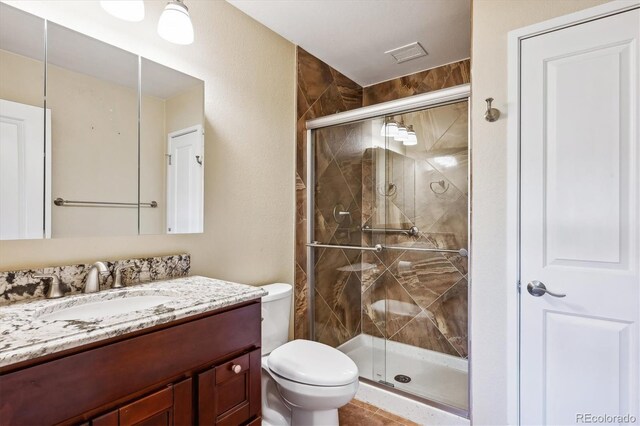 bathroom with vanity, toilet, and a shower with door