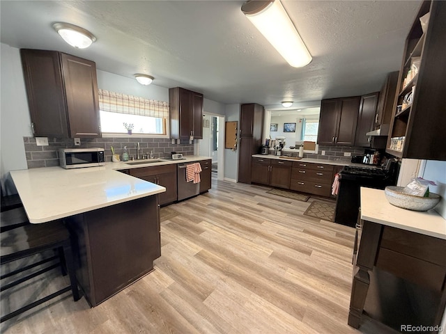 14 W 3rd St, Flagler, CO 80815 - kitchen featuring stainless steel appliances, a sink, tasteful backsplash, light countertops, and a peninsula