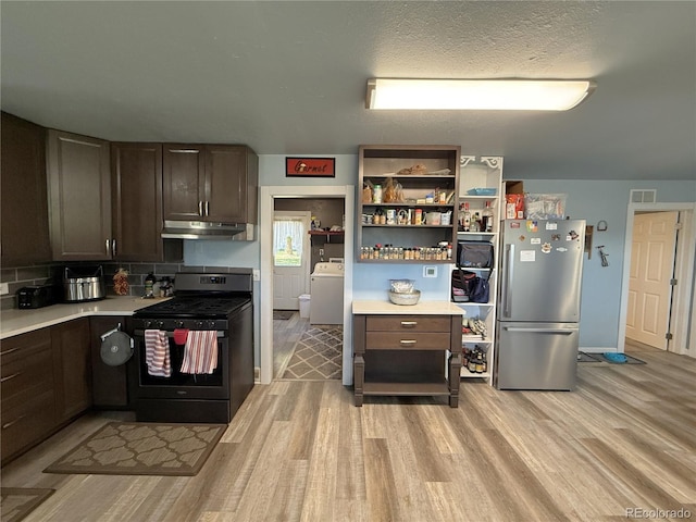 14 W 3rd St, Flagler, CO 80815 - kitchen with freestanding refrigerator, gas stove, under cabinet range hood, washer / clothes dryer, and light wood finished floors
