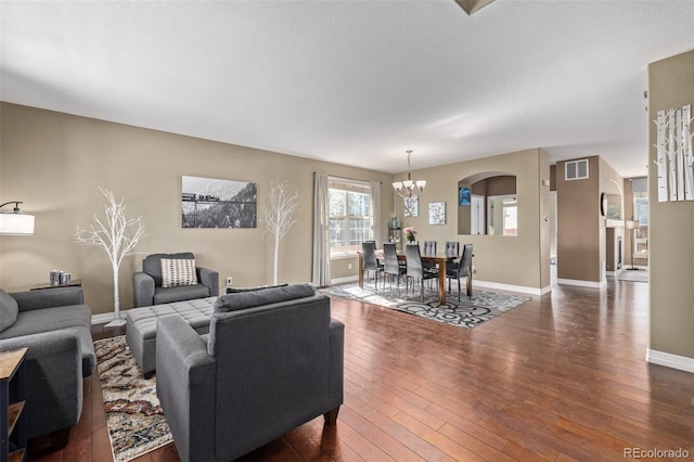 living room with a notable chandelier, baseboards, dark wood finished floors, visible vents, and arched walkways