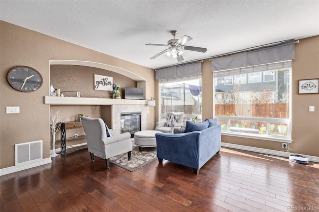 living room featuring visible vents, a ceiling fan, wood-type flooring, and a textured wall