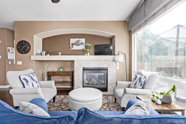 living area with a tile fireplace, wood finished floors, and baseboards