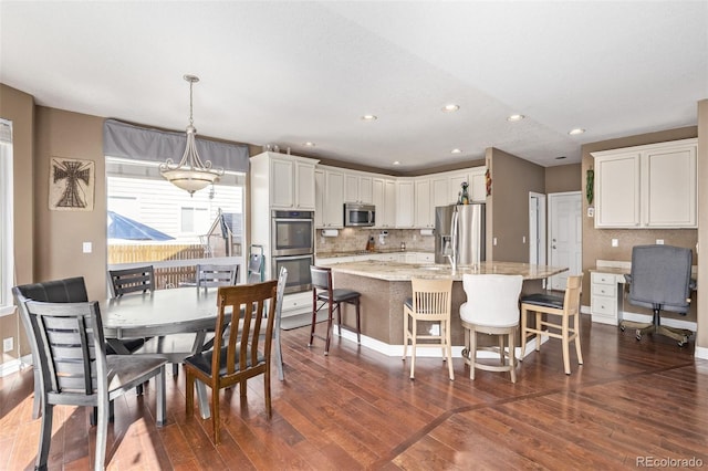 kitchen featuring white cabinets, appliances with stainless steel finishes, hanging light fixtures, and dark wood-type flooring