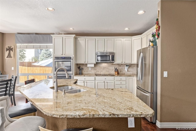 kitchen featuring a breakfast bar area, a sink, white cabinetry, appliances with stainless steel finishes, and tasteful backsplash