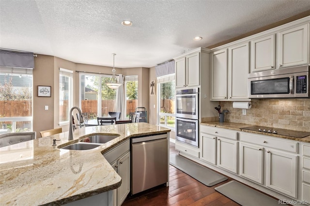 kitchen with a textured ceiling, appliances with stainless steel finishes, dark wood-style floors, and a sink