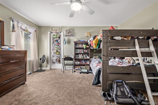 bedroom with ceiling fan, carpet flooring, and a textured ceiling