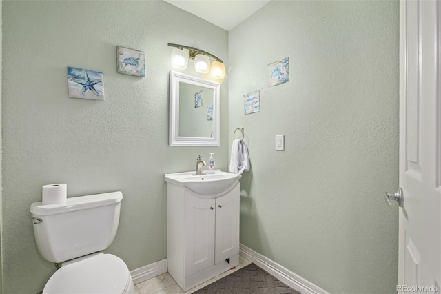 bathroom with toilet, baseboards, and vanity