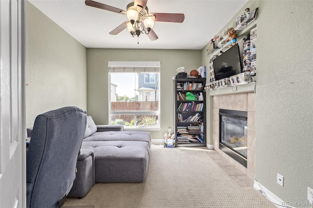 living area with a tile fireplace, carpet flooring, ceiling fan, and a textured wall