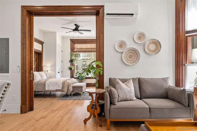 living room with a wall mounted air conditioner, ceiling fan, and wood finished floors