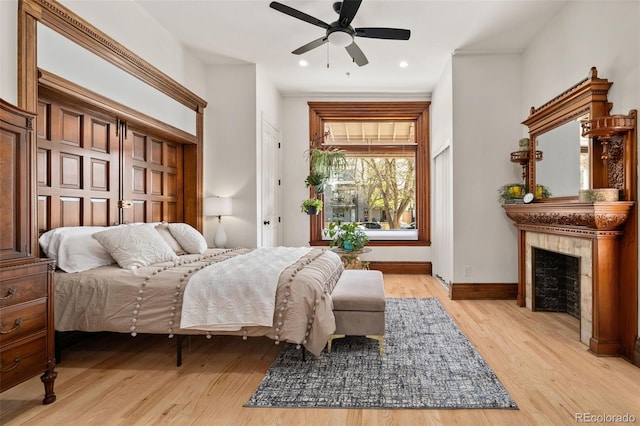 bedroom featuring recessed lighting, a ceiling fan, baseboards, a fireplace, and light wood-style flooring