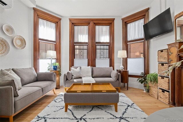 living room featuring light wood-type flooring and an AC wall unit