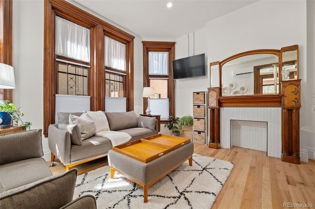 living room featuring baseboards, wood finished floors, a wall mounted AC, and recessed lighting