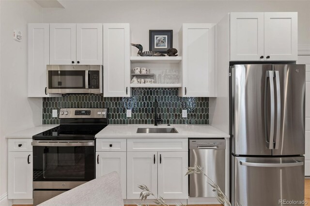 kitchen featuring white cabinets, light countertops, appliances with stainless steel finishes, and a sink
