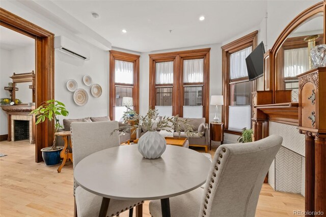 dining area featuring a fireplace, recessed lighting, light wood-style floors, and a wall mounted air conditioner
