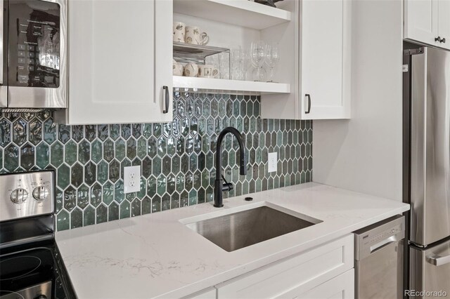 kitchen featuring white cabinets, appliances with stainless steel finishes, open shelves, and a sink