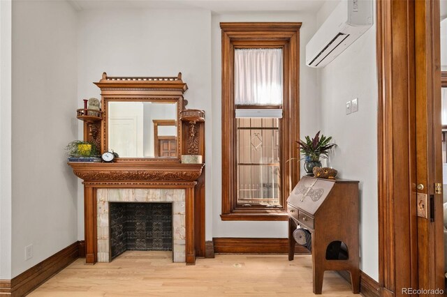 interior space featuring baseboards, wood finished floors, a fireplace, and a wall mounted air conditioner