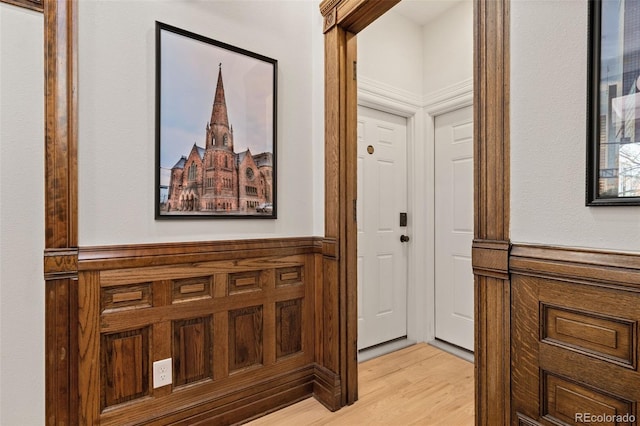 hall featuring light wood-type flooring and a wainscoted wall