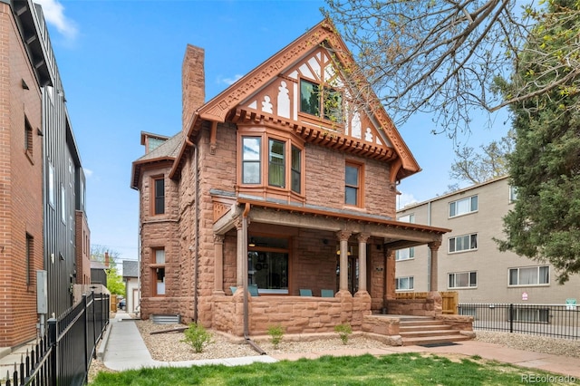 view of front of house featuring fence, a chimney, and stone siding