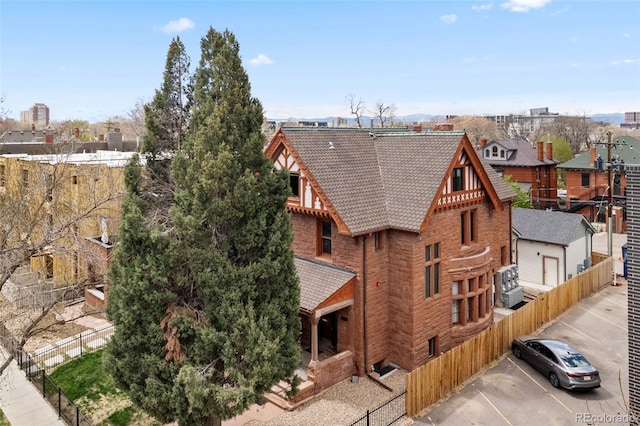 view of home's exterior with a residential view, a tiled roof, brick siding, fence private yard, and uncovered parking