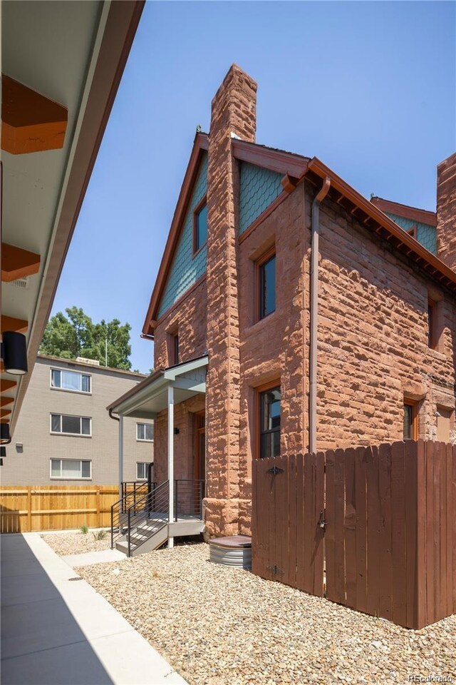 view of home's exterior with a chimney, fence, and a porch