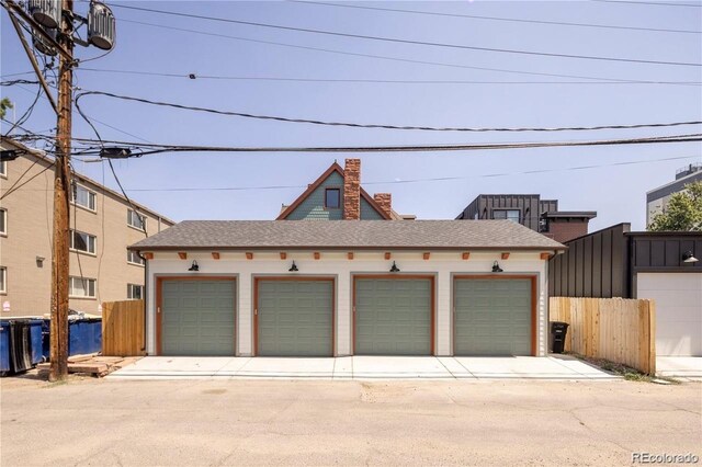 view of front of property with community garages, a chimney, and fence