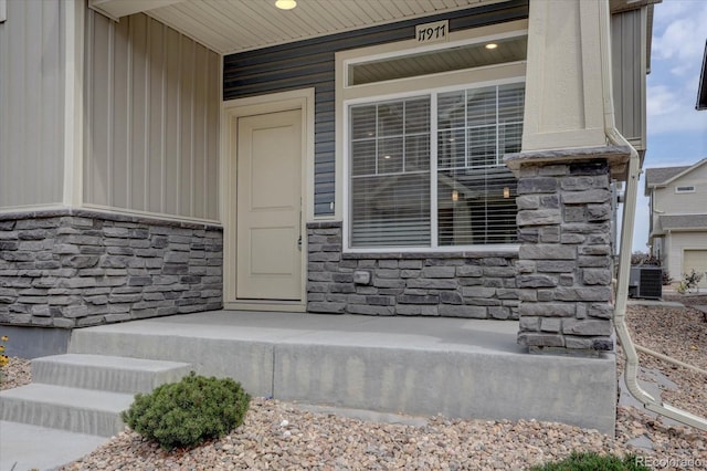 view of exterior entry featuring cooling unit and covered porch