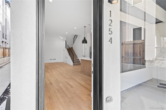 corridor with stairs, visible vents, and wood finished floors