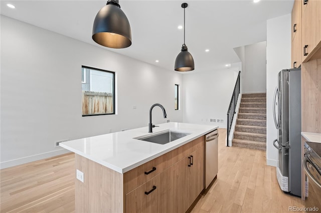 kitchen with decorative light fixtures, stainless steel appliances, a sink, light countertops, and a center island with sink