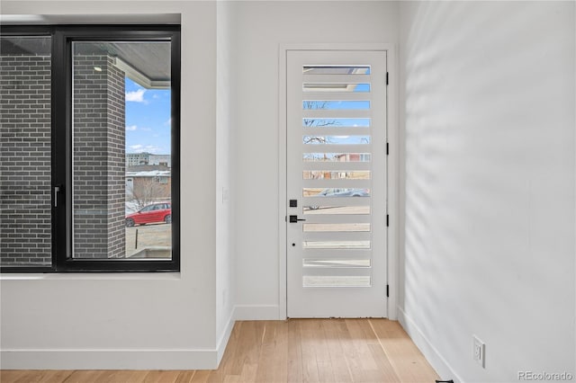 doorway to outside with light wood-style flooring and baseboards