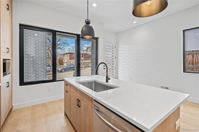 kitchen featuring a sink, light countertops, appliances with stainless steel finishes, an island with sink, and pendant lighting