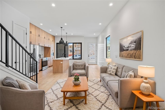 living room with recessed lighting, light wood-style flooring, and stairs