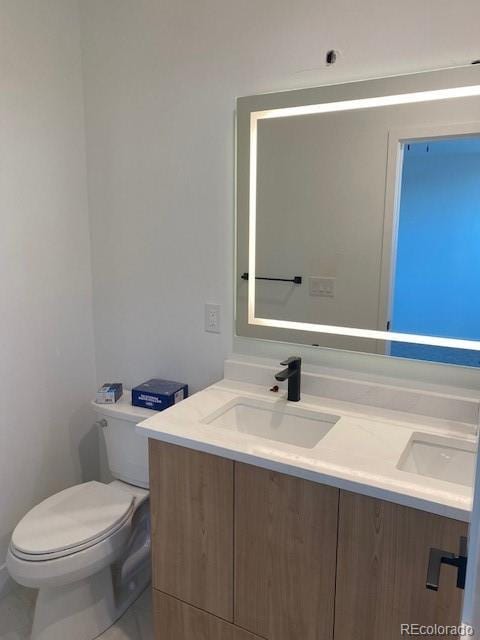 bathroom featuring toilet, double vanity, and a sink